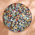 Bahja zellige tabletop seen from above, hand-cut eight-point stars in cobalt, turquoise, green, burgundy, saffron and red with a border of coloured tiles