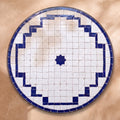 Hashiya zellige tabletop seen from above, a white top with a cobalt stepped border and one centre star, inspired by Fez embroidered hems