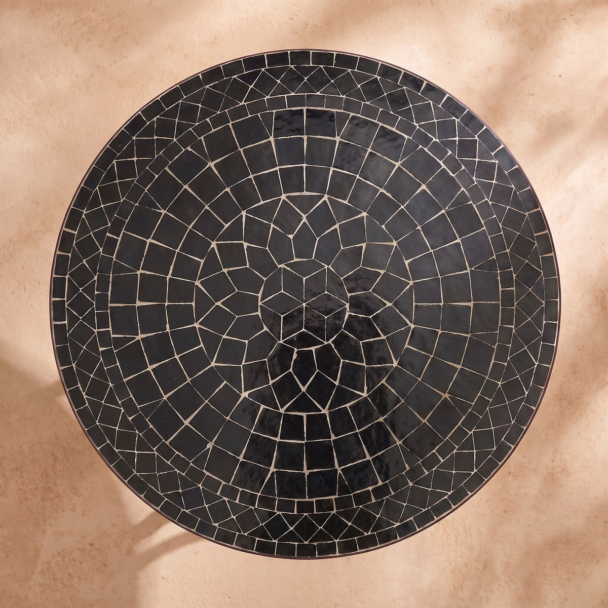 Kahla zellige mosaic side table seen from above, concentric rings of glossy black hand-cut tiles with pale joints, colour rendering of the design