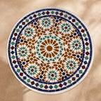 Kawkab handmade Beldi zellige tabletop seen from above, honey amber star ringed by green hexagons and stars inside a navy ring and white diamond border