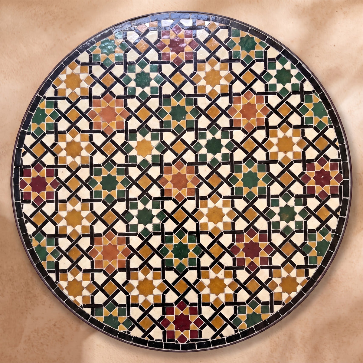 Meknassia zellige tabletop seen from above, warm red, ochre and green stars outlined in black strips on cream, inspired by Meknès embroidery