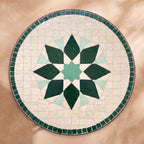 Rihan zellige tabletop seen from above, Rabat lozenge-petal flower in tonal greens on white