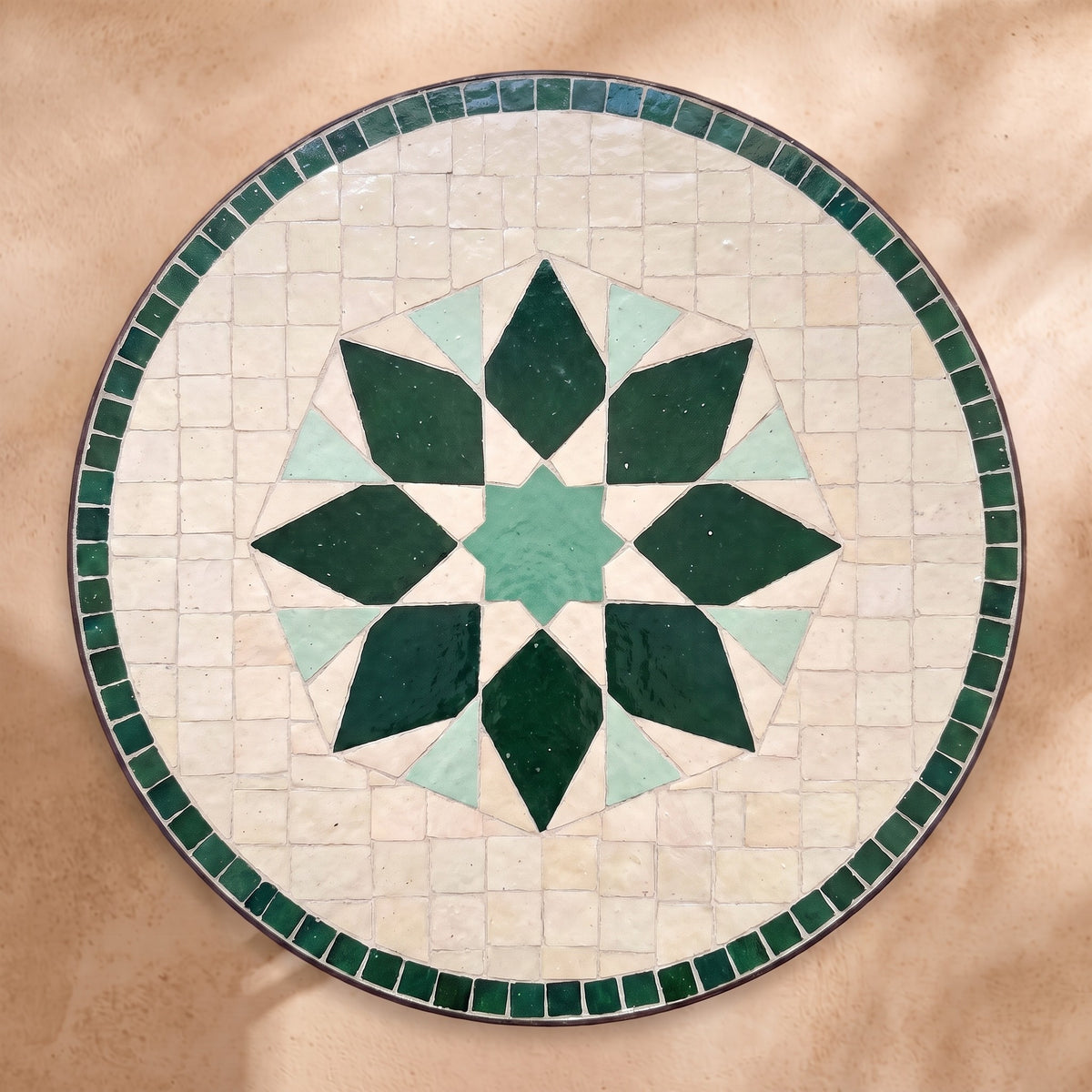 Rihan zellige tabletop seen from above, Rabat lozenge-petal flower in tonal greens on white