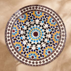 Warda handmade Beldi zellige tabletop seen from above, burgundy sixteen-point star rosette with sky blue, saffron and navy petals inside an aubergine border