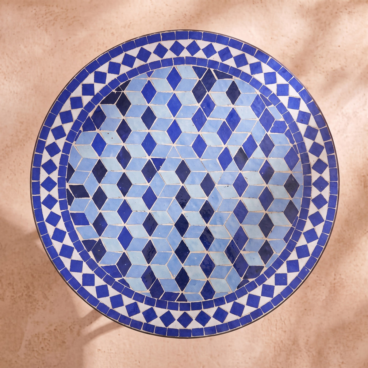 Zarqa zellige mosaic side table seen from above, tumbling cubes in Majorelle blue, cobalt and sky blue with a blue and white diamond border, colour rendering of the design